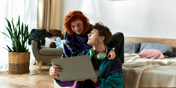 Junge Studentin und junger Student, die glücklich auf einen Laptop schauen.