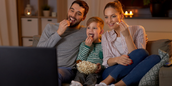 Familie isst Popcorn und schaut dabei einen Film.